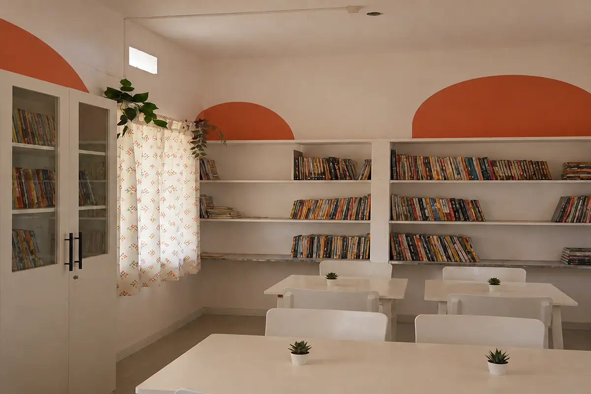 The Ajani library after renewal, with book cabinets, reading tables, chairs and warm terracotta arches
