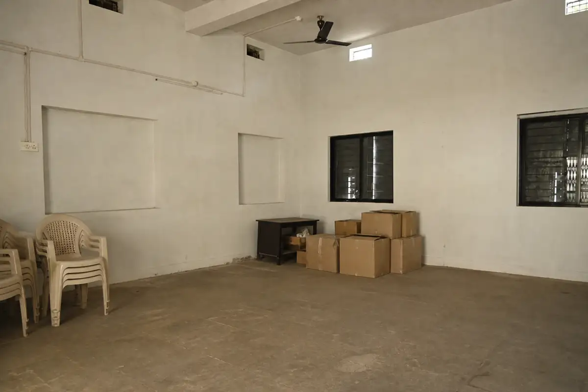 The Deolapar room before renewal, with stacked cartons, plastic chairs and empty wall recesses
