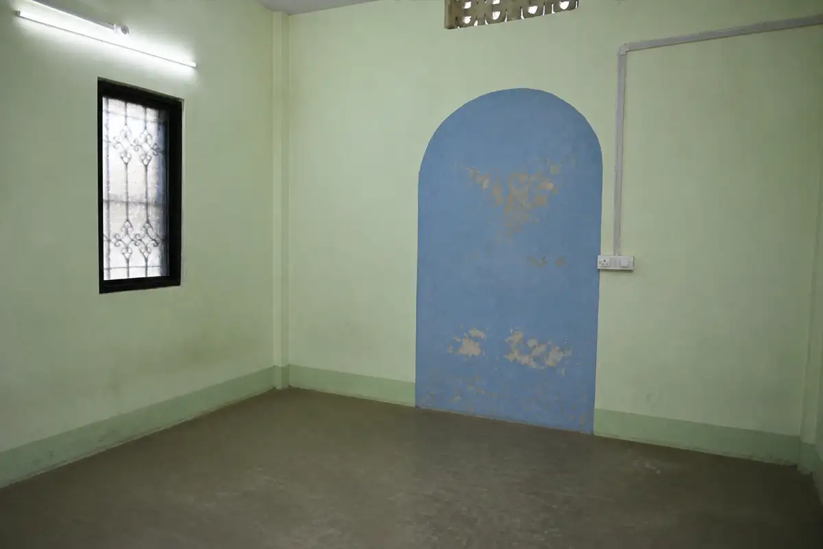 The Wadamba room before renewal, with an unfinished floor and a worn blue arched wall detail